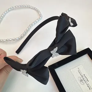 Serre-tête en satin noir élégant avec trois papillons en strass sur fond de perles