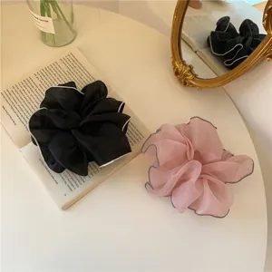 Lot de chouchous en tulle noir et rose présentés sur une table blanche avec miroir et livre