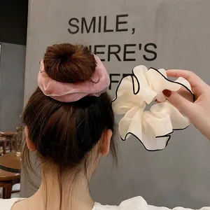 Détail de chouchous en organza rose et beige avec bordure contrastée sur les cheveux