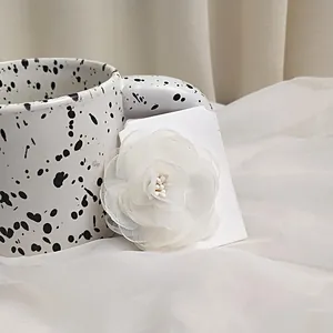 Detailed close-up of multi-layer white camellia hair clip on artistic card packaging