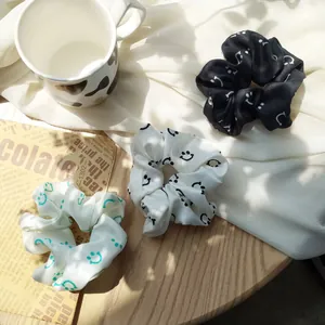 Detailed view of satin scrunchie set with minimalist smiley patterns in three colors