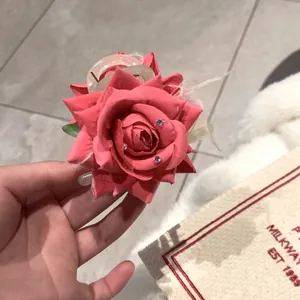 Détail de la pince à cheveux rose avec strass, plumes et feuilles vertes