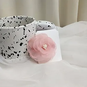 Detailed view of sweet pink camellia hair clip with layered tulle and white stamen