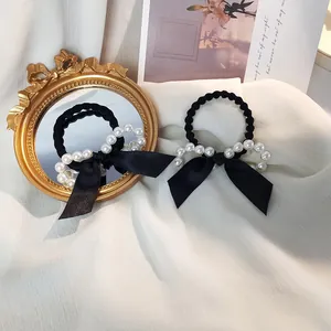 Détails d'élastiques à cheveux noirs avec nœuds et perles sur fond de tissu doux