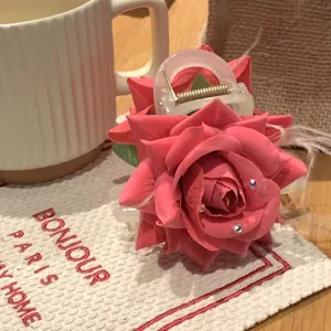 Détail d'une pince à cheveux rose en forme de rose avec strass sur une table élégante