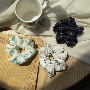 Three-piece set of silk scrunchies with smiley face patterns on a rustic wooden table