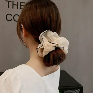 Chouchou chic en tulle crème avec bordure noire contrastée porté en queue de cheval