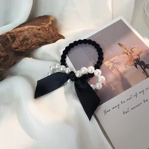 Détail d'un chouchou en satin noir avec perles blanches élégantes sur tissu doux