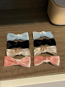 Set of eight velvet bow hair clips in four pastel colors on a dark wooden surface