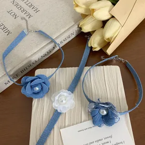 Collana girocollo con rose in denim e pizzo con perle su sfondo di libri d'epoca e tulipani