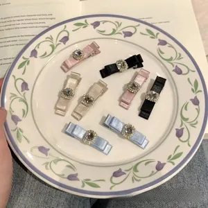 Macro view of satin bow hair clips with crystal center decorations in a porcelain bowl