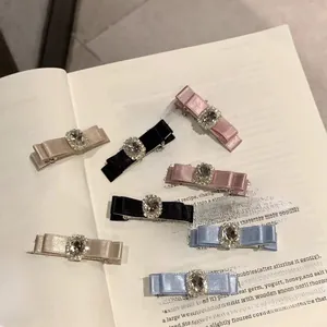 Set of six satin ribbon bow hair clips with rhinestones and crystals on a book