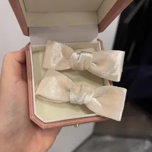 Detail of pink velvet bow hair clips with pearls displayed in an octagonal jewelry box