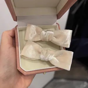 Elegant cream velvet bow hair clips presented in a pink octagonal gift jewelry box
