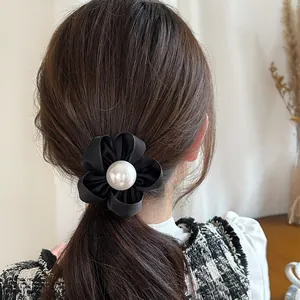Élastique à cheveux fleur en satin noir avec perle blanche élégante sur une queue de cheval