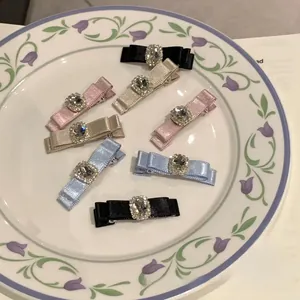 Detailed view of six satin bow hair clips with rhinestones in a decorative tray