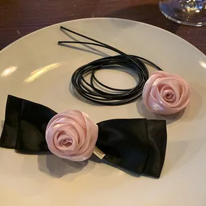 Elegant set with pink silk rose bow hair clip and matching choker on a white ceramic plate