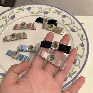 Detailed close-up of bow hair clips with large rhinestones and metal duckbill clips