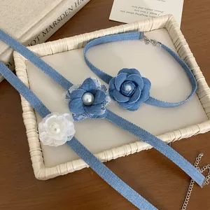 Dettaglio di collane con rose in denim, perle e pizzo su tavolo in legno vintage