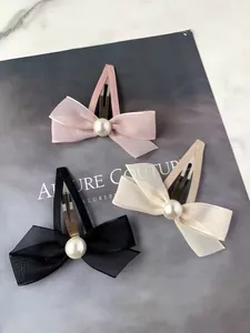 Détail de barrettes nœuds rose, noir et crème avec perles sur une page de magazine