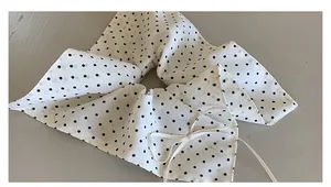 Detailed view of white polka dot chiffon scrunchie with elegant ribbons and bow detail