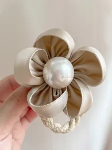 Détail de l'élastique à cheveux camélia en soie champagne avec une perle centrale