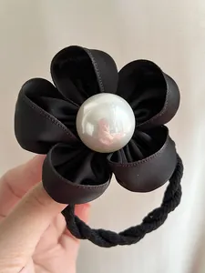 Détail d'un chouchou fleur en satin noir avec centre en perle et cordon élastique robuste