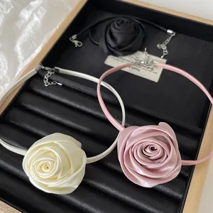 Detailed shot of handmade fabric rose necklaces in cream, pink and black on display