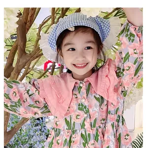 Detail of blue gingham bonnet and pink floral dress for girls in a scenic garden