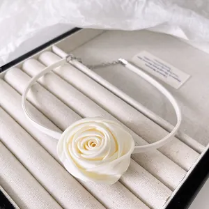 Detail view of a creamy white satin rose choker with silver metal adjustable chain