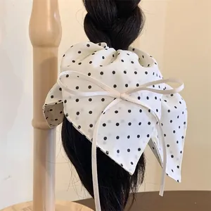 Retro oversized white polka dot scrunchie with long ribbon bow on black braided hair