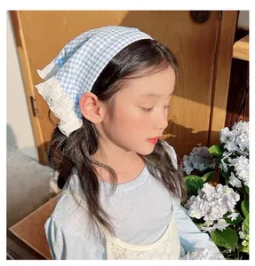 Detailed view of a blue gingham lace bandana headscarf for girls in a rustic garden setting
