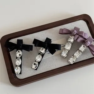 Elegante Haarklammern mit Satinschleifen und glitzernden Kristallen in Lila und Schwarz