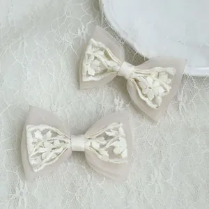 Detail of elegant white lace bow hair clips with intricate floral embroidery and tulle