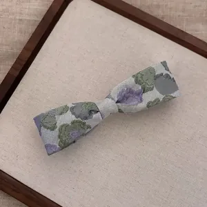 Detailed close-up of a floral embroidered bow hairpin with vintage jacquard fabric texture