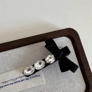 Eleganter schwarzer Samt-Haarclip mit funkelnden Kristallen auf einem Holztablett