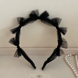 Close-up of black lace mesh headband with elegant butterfly bows and pearl accents