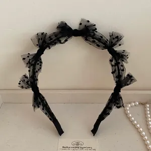 Detail of black mesh lace headband featuring polka dots and layered bow design