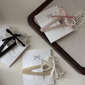 Vintage velvet bow hair clips with pearls in black, pink, and beige on a display card