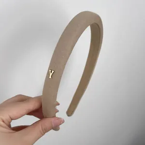Serre-tête rembourré en tissu beige avec un élégant accent métallique en forme de Y