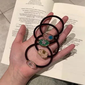 Haargummi-Set mit Trockenblumen aus Harz und Goldfolie auf einem Vintage-Buch