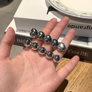 Detail of silver heart and bead hair clips held in hand for hair styling
