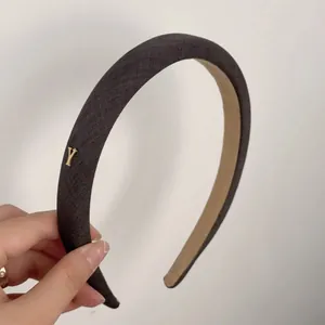 Serre-tête large en peluche marron avec élégant détail métallique doré de la lettre Y
