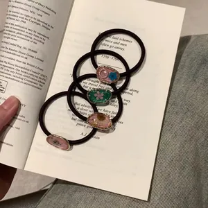 Set mit vier handgefertigten Blumen-Haargummis aus Harz auf einem Vintage-Buch