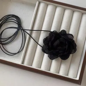 Dettaglio di una collana artigianale con rosa 3D in tessuto nero e petali di chiffon