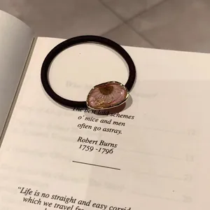 Nahaufnahme eines Haargummis mit rosa Blüten und Goldfolie auf einem Buch