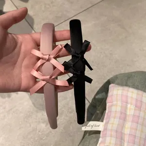 Détail de serre-têtes en satin rose et noir mat avec un design à trois nœuds élégants