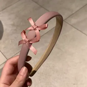 Détail d'un serre-tête en satin rose avec double nœud et doublure antidérapante en velours