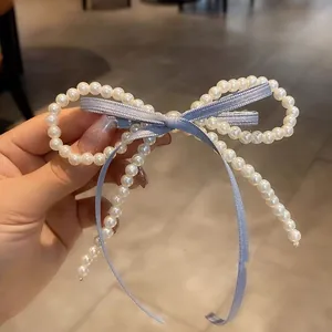 Detailed macro view of white pearl beads and light blue ribbon bow hair clip design