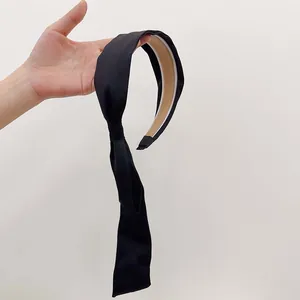 Detail showing smooth black satin headband with long flowing ribbon and non-slip lining